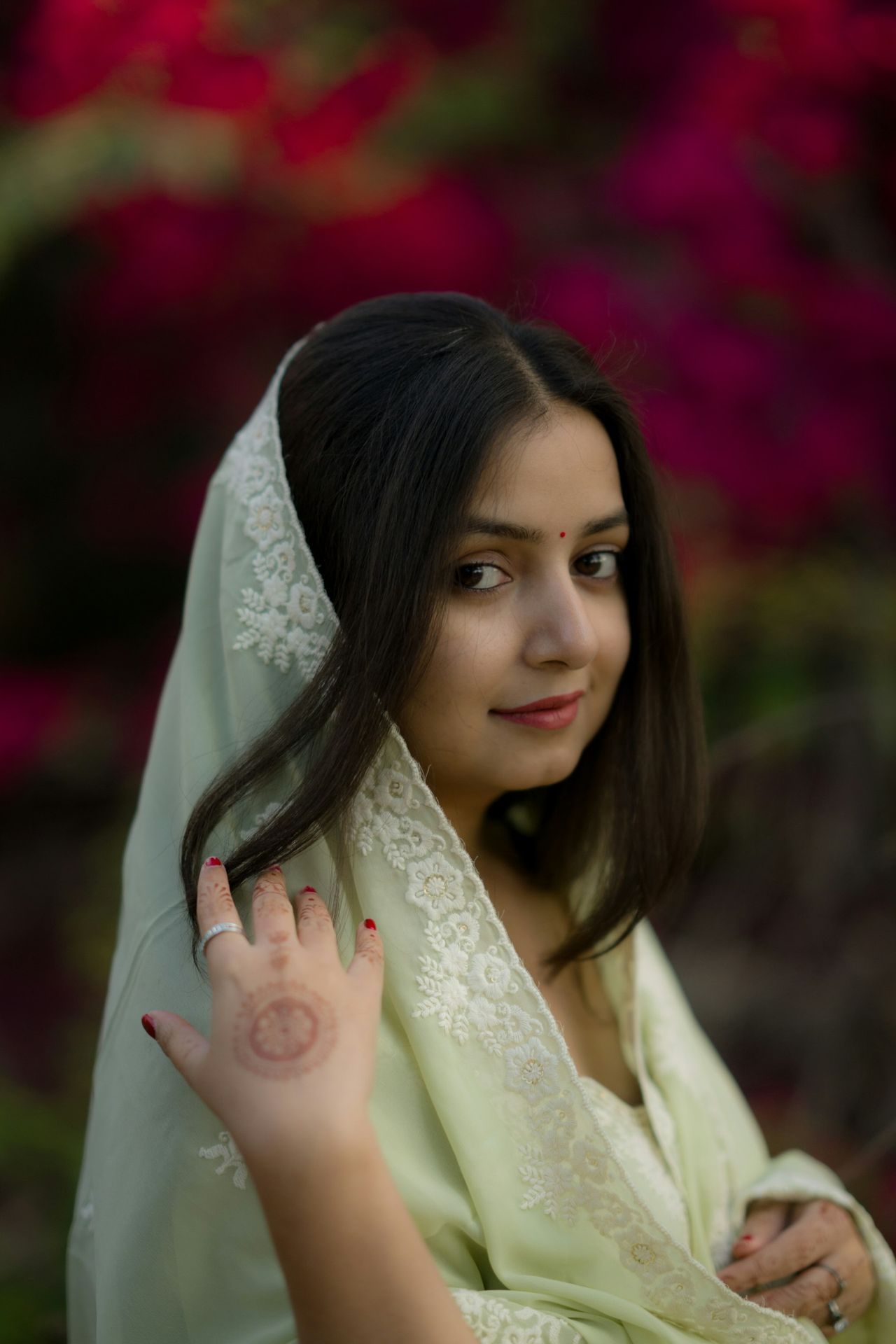 A woman poses in a beautiful, floral background.